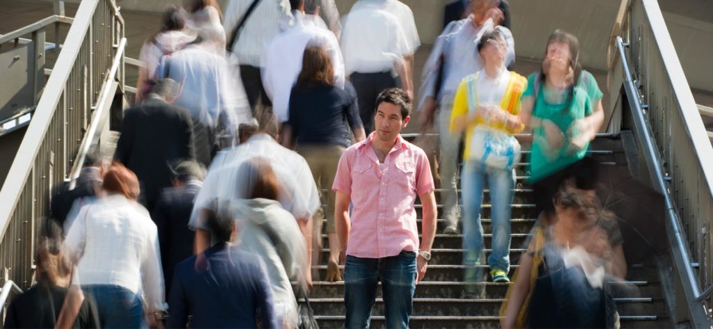 man standing still on the stairs while others move